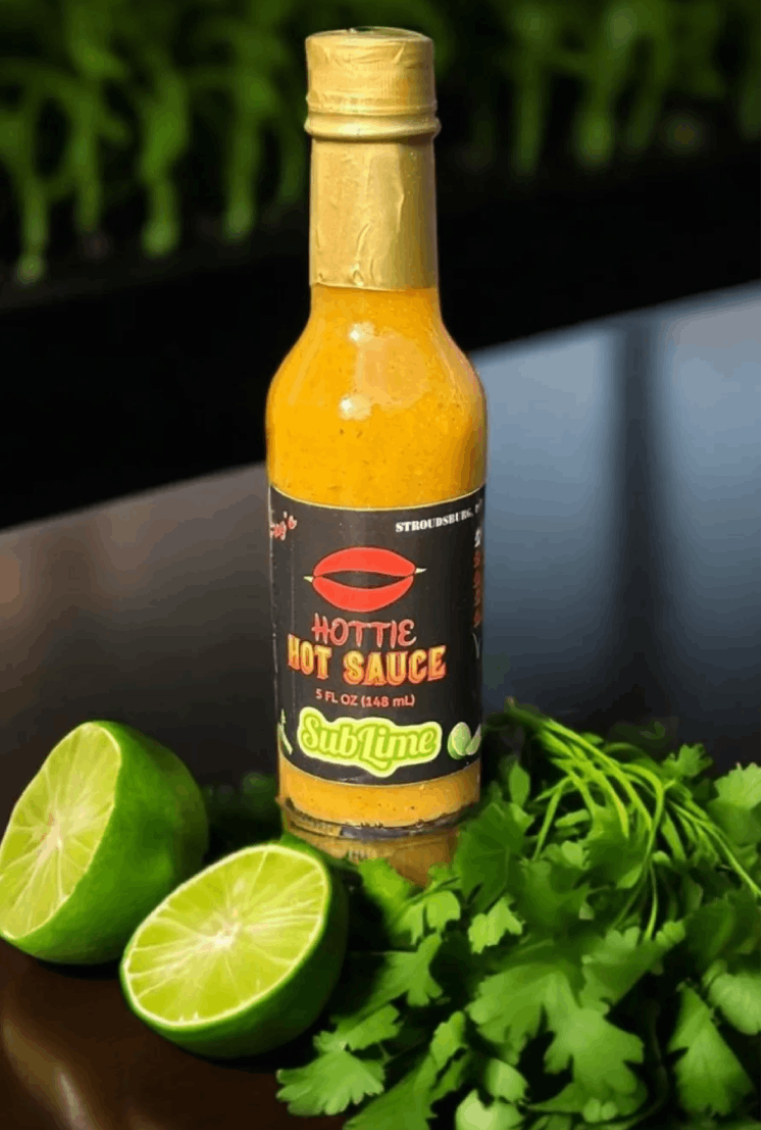 A bottle of hot sauce sitting on top of some limes.