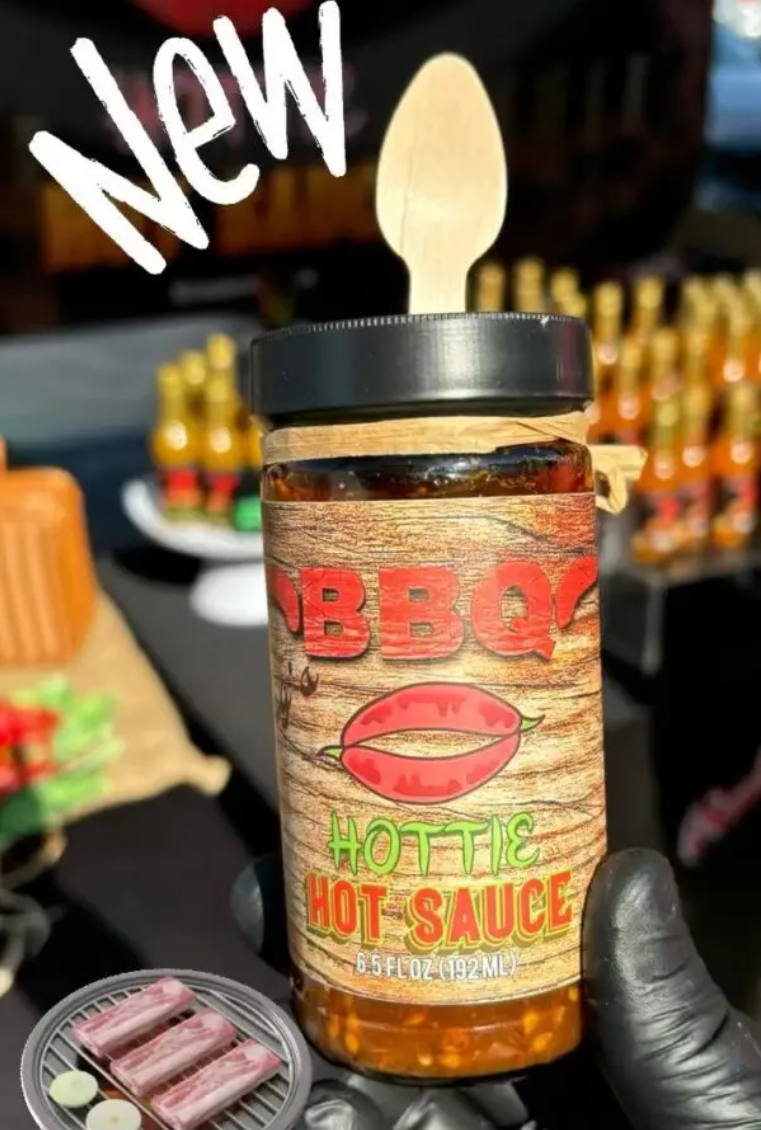 A hot sauce container with a wooden spoon sticking out of it.