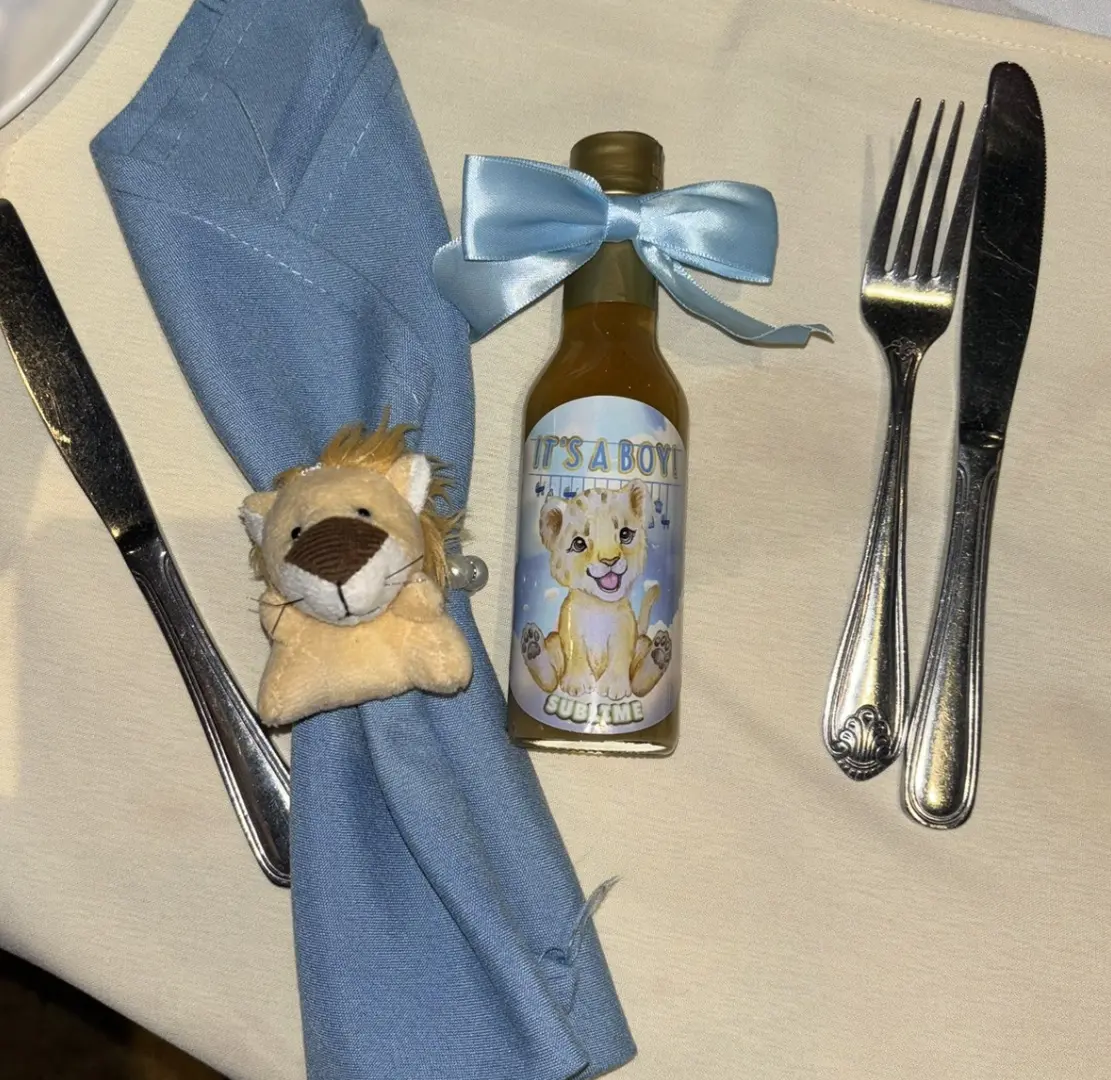 A table with silverware, knife and fork, napkin, bottle of mustard and stuffed animal.