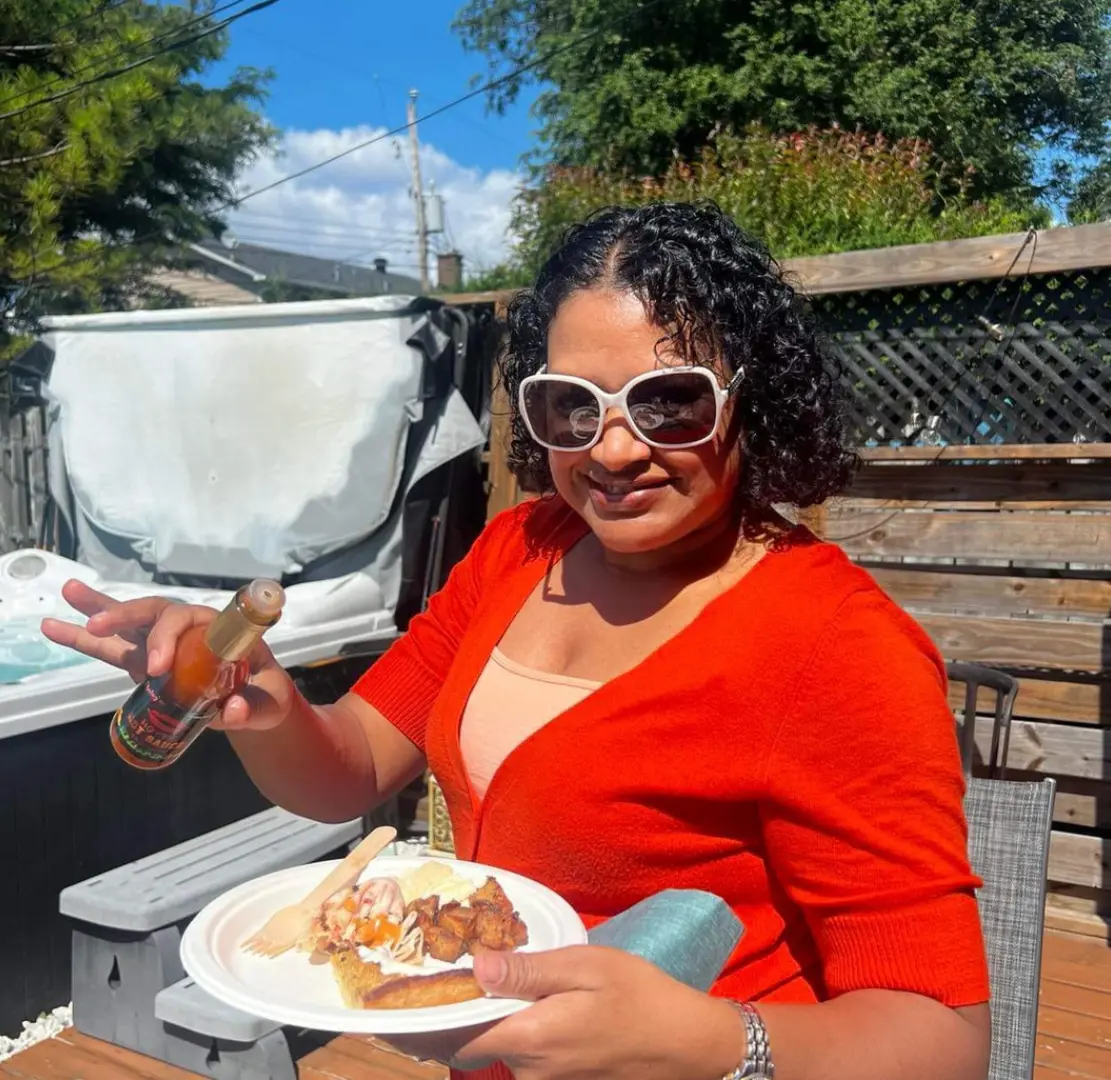 A woman in red shirt holding plate of food.